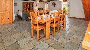 A dining area with a wooden table set for four, surrounded by chairs with cushioned seats. - 3 bedroom accommodation in Catfield (Catfield)