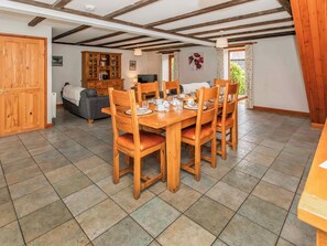 A dining area with a wooden table set for four, surrounded by chairs with cushioned seats.