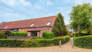 A brick house with a tiled roof, a gravel driveway, and a hedge. - 3 bedroom accommodation in Catfield (Catfield)