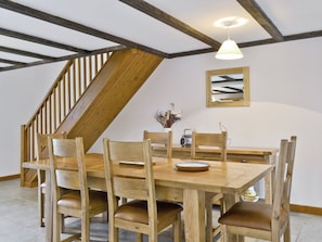 A dining area with a wooden table and chairs, a radio, and a vase with dried flowers. - 3 bedroom accommodation in Catfield (Catfield)