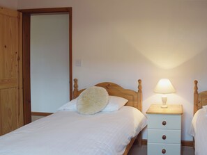 Ein Schlafzimmer mit einem Holzbett, einem Nachttisch mit Lampe und einem Kleiderschrank.