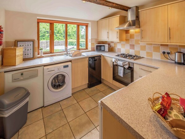 A modern kitchen with a dishwasher, washing machine, microwave, and stove.