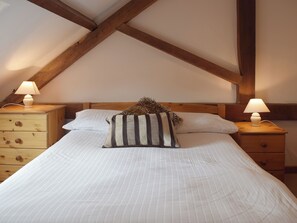 A bedroom with a bed, two nightstands, and a wooden ceiling.