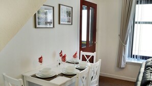 A dining area with a white table set for four, white chairs, and a red door. - 2 bedroom accommodation in Moffat (Moffat)
