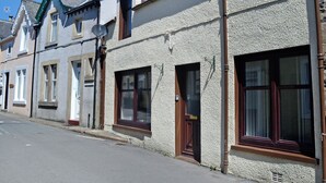 A row of townhouses with pitched roofs, satellite dishes, and a clear blue sky. - 2 bedroom accommodation in Moffat (Moffat)