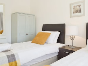 A hotel room with a bed, a nightstand with a lamp, a wardrobe, and a framed picture on the wall.