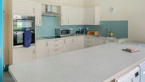 Une cuisine moderne avec des meubles blancs, un four encastré, un four à micro-ondes et un lave-linge.