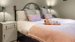 A neatly made bed with a pink blanket, two bedside lamps, a small cabinet, and a framed picture on the wall. - 2 bedroom accommodation in Thorncliffe, near Leek (Thorncliffe, near Leek)