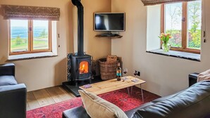 A cozy living room with a fireplace, a television, and a view of the outdoors. - 2 bedroom accommodation in Thorncliffe, near Leek (Thorncliffe, near Leek)