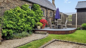 A stone building with a garden area, a wooden deck, and a fenced play area. - 2 bedroom accommodation in Thorncliffe, near Leek (Thorncliffe, near Leek)