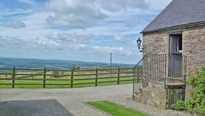 A stone building with a gravel driveway, a wooden fence, and a view of rolling hills. - 2 bedroom accommodation in Thorncliffe, near Leek (Thorncliffe, near Leek)
