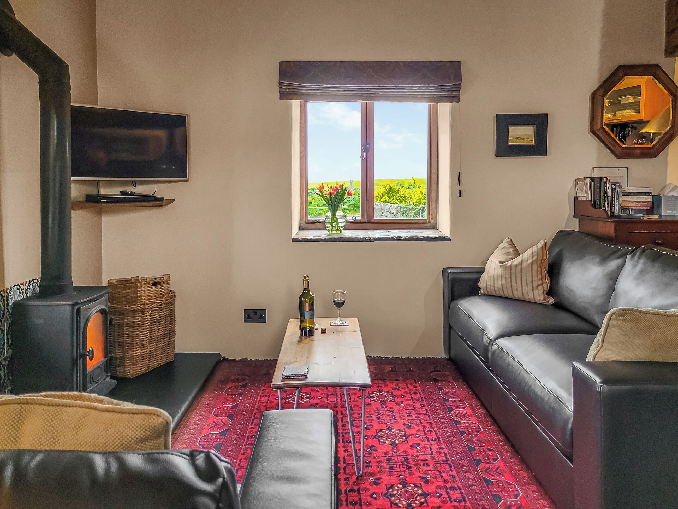 A living room with a fireplace, a sofa, a coffee table, and a window with a view of greenery.