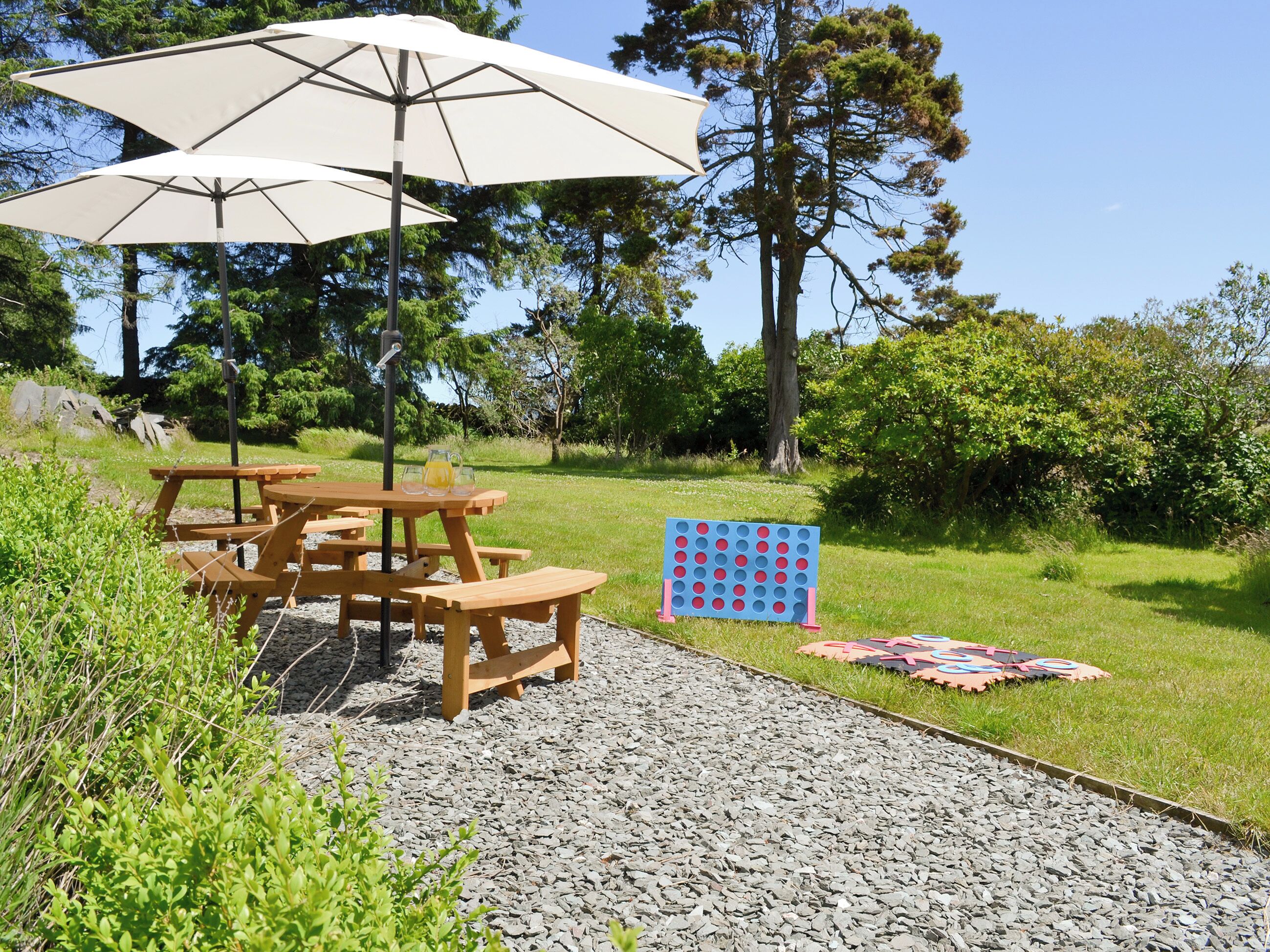 A picnic setup with a table, benches, and a board game on a gravel path.