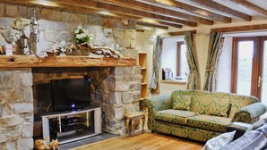 Una chimenea de piedra con un televisor, un sofá estampado color verde y un sofá de cuero.