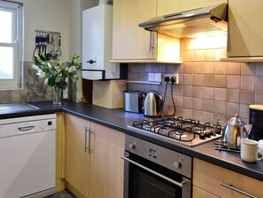 A kitchen with a Bosch dishwasher, a gas stove, a kettle, and a toaster.