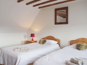 Une chambre avec deux lits, une table de chevet avec une lampe et un miroir au mur.