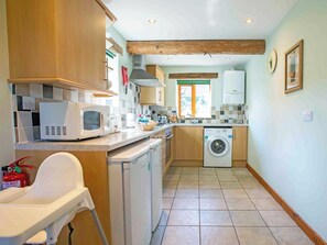 Een compacte keuken met een wasmachine, magnetron en een klein eethoekje.