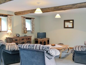 Ein gemütliches Wohnzimmer mit Holzboden, einem Fernseher und einem Holzschrank.