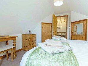 A bedroom with a bed, a wooden dresser, a desk, and a mirror. - 2 bedroom accommodation in Catfield (Catfield)