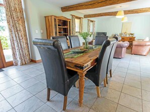A dining area with a wooden table, black chairs, and a floral curtain.