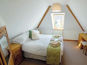 A bedroom with a bed, a wooden nightstand, a dresser, a window with a view, and a hanging lamp.