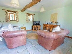 A living room with two sofas, a television, and a wooden cabinet with decorative items. - 2 bedroom accommodation in Catfield (Catfield)