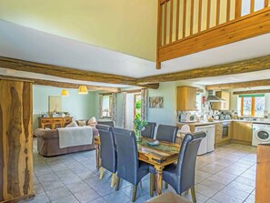 A spacious living area with a dining table and chairs, a sofa, and a wooden cabinet.