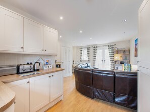 A modern kitchen with white cabinets, a wooden countertop, and a built-in oven.