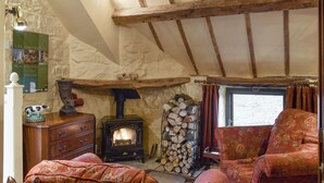 A cozy room with a stone wall, wooden beams, a fireplace, a sofa, and a dresser. - 0 bedroom accommodation in Glaisdale, near Whitby (Glaisdale, near Whitby)