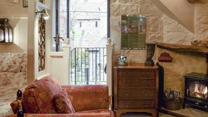 A cozy room with a fireplace, a wooden dresser, and a floral sofa. - 0 bedroom accommodation in Glaisdale, near Whitby (Glaisdale, near Whitby)