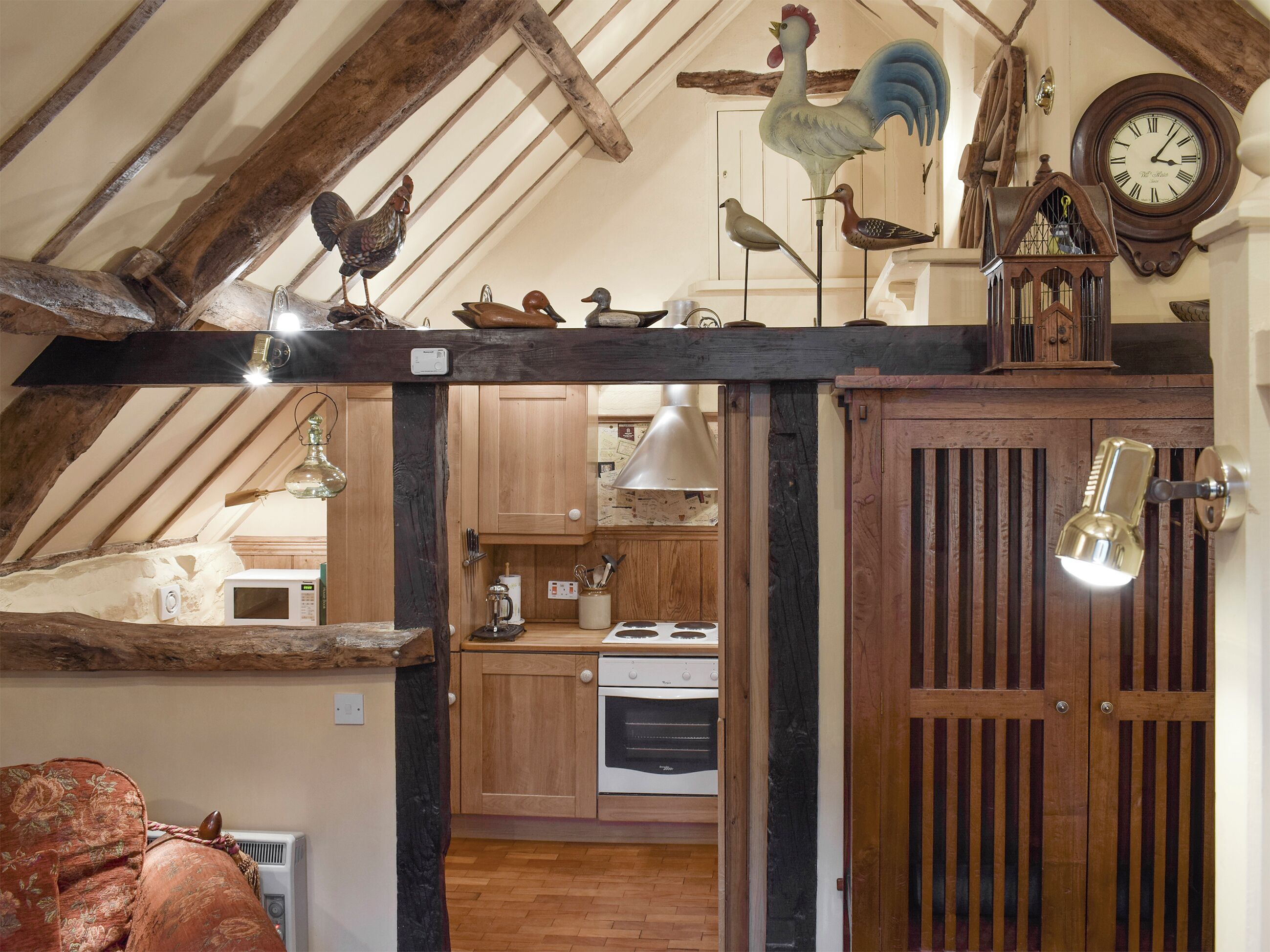 A rustic kitchen with wooden beams, a clock, and decorative chickens.