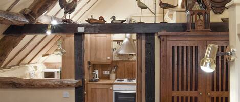 A rustic kitchen with wooden beams, a clock, and decorative chickens.