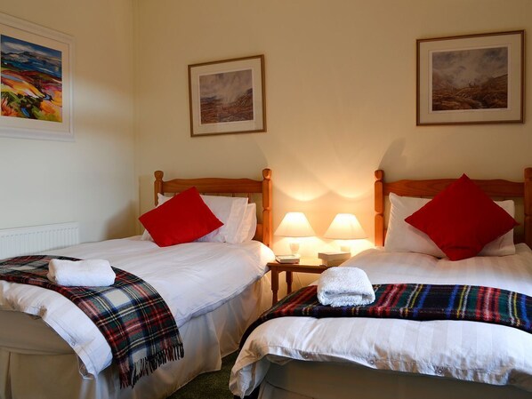 A double room with two beds, each with white linens and red pillows. There are two bedside tables with lamps, and the room has a simple, clean design. - Inverchroskie Cottage (Enochdhu, near Pitlochry)