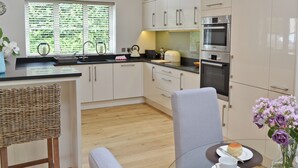 A modern kitchen with white cabinets, a stainless steel oven, and a dining area with a table set for two.