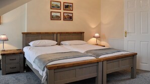 A bedroom with a wooden bed, two bedside tables with lamps, and a door. - 3 bedroom accommodation in Keswick (Keswick)