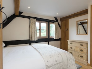 A bedroom with a bed, a dresser, a window with curtains, and a mirror on the wall. - Parker’s dates from 1610 and is part of the 700-acre Netherley Hall Estate. (Mathon, near Malvern)