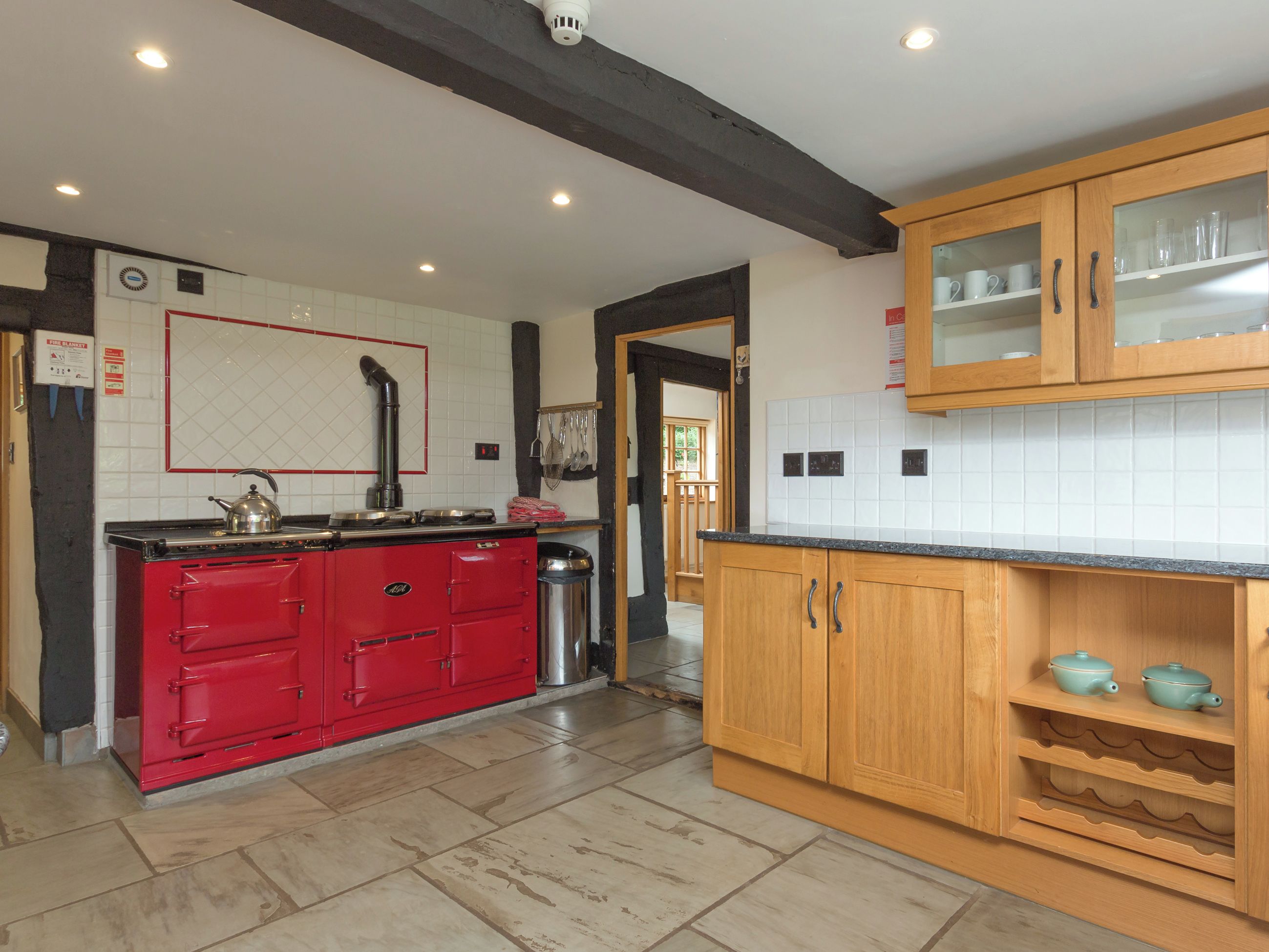Een keuken met een rode kookplaat, houten kastjes en een betegelde spatwand.