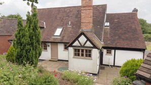 A traditional house with a gabled roof, a chimney, and a small attached shed. - Parker’s dates from 1610 and is part of the 700-acre Netherley Hall Estate. (Mathon, near Malvern)