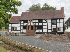 A traditional half-timbered house with a gravel driveway, a wooden door, and a small patio with chairs. - Parker’s dates from 1610 and is part of the 700-acre Netherley Hall Estate. (Mathon, near Malvern)