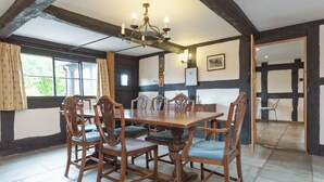 A dining room with a wooden table and chairs, a chandelier, and a view through a window. - Parker’s dates from 1610 and is part of the 700-acre Netherley Hall Estate. (Mathon, near Malvern)