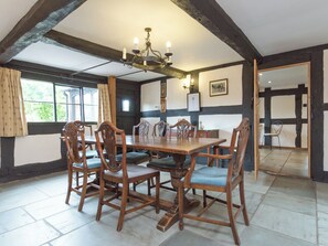 A dining room with a wooden table and chairs, a chandelier, and a view through a window. - Parker’s dates from 1610 and is part of the 700-acre Netherley Hall Estate. (Mathon, near Malvern)