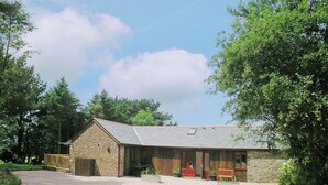 Un bâtiment en pierre avec un toit en pente, une véranda et une allée gravillonnée.