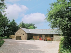 A stone building with a sloped roof, a covered porch, and a gravel driveway. - 2 bedroom accommodation in Hartland (Hartland)