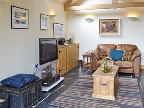 Ein Wohnzimmer mit Fernseher, Holzschrank, Ledersofa und Couchtisch.