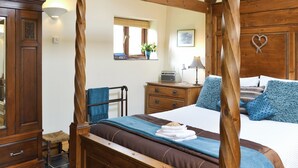Un lit à baldaquin avec un cadre en bois, une table de chevet avec une lampe, une radio et un miroir au mur.