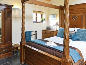 A four-poster bed with a wooden frame, a bedside table with a lamp, a radio, and a mirror on the wall. - 2 bedroom accommodation in Hartland (Hartland)