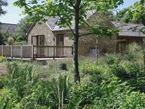 A stone building with a wooden deck and a stone wall. - 2 bedroom accommodation in Hartland (Hartland)