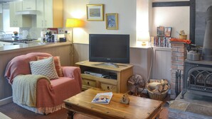 A cozy living room with a TV, a fireplace, and a dining area. - 2 bedroom accommodation in Pen-y-Sarn, near Amlwch (Pen-y-Sarn, near Amlwch)