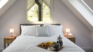 A neatly made bed with white linens, a breakfast tray with croissant, orange juice, and coffee, and two bedside lamps. - 3 bedroom accommodation in Muthill, near Crieff (Muthill, near Crieff)