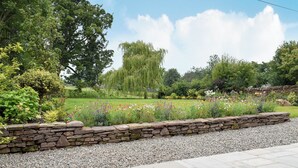 A garden with a stone wall, gravel path, and various plants. - 3 bedroom accommodation in Muthill, near Crieff (Muthill, near Crieff)